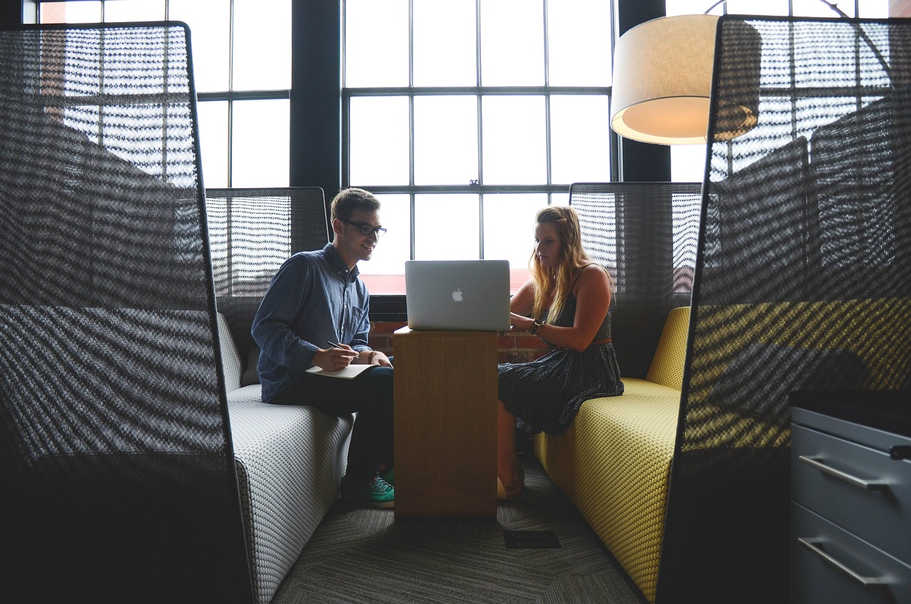 A man and a woman sitting with a laptop, engaged in discussion, representing the flexibility and collaboration of AaaS.