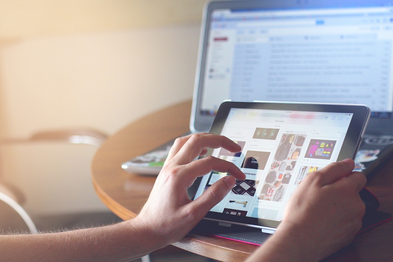 A hand operating a tablet with a computer in the background, symbolizing digital transformation and modular IT architecture.